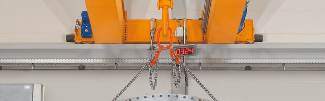 Sommier équipé d'embouts d'un pont, à lequel est fixé un élingue à chaîne avec une charge.