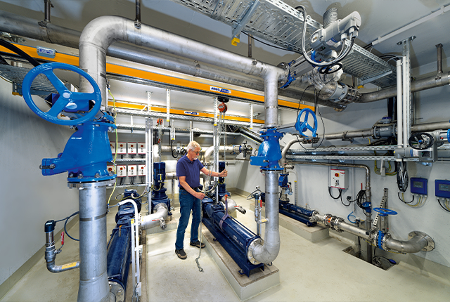 Un employé utilise un système de voie suspendue équipé d'un palan à chaîne et déplace une charge dans un atelier