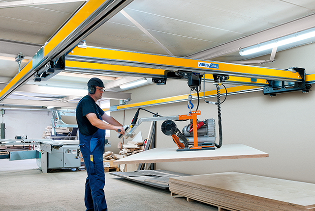 Un employé utilise un pont bipoutre ZHB-X et effectue le levage d'une charge à l'aide d'un palan à chaîne dans un atelier.