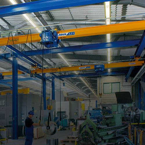 Ponts roulants suspendus ABUS dans un hall industriel, d'une capacité de charge allant jusqu'à 8 tonnes et d'une portée allant jusqu'à 25 mètres, pour un transport de matériaux peu encombrant.